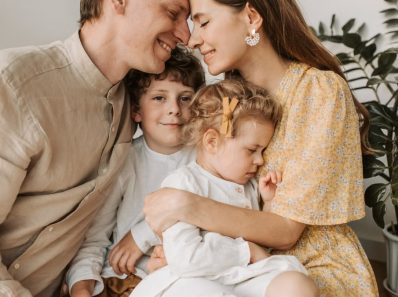 A loving family of four shares a tender moment in a cozy indoor setting, embracing and smiling.